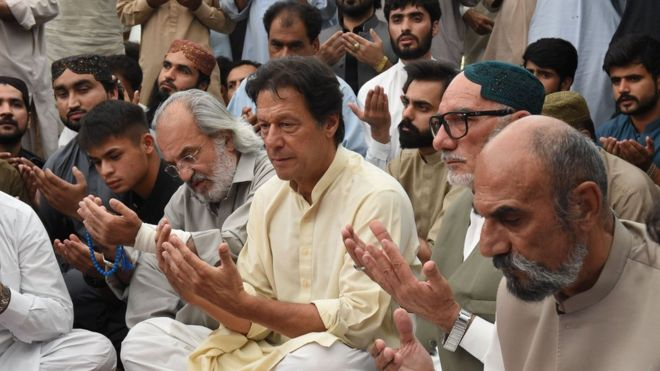 Pakistani cricketer-turned-politician and head of the Pakistan Tehreek-i-Insaf (PTI) Imran Khan (L) prays with elder brother Aslam Raisani of Siraj Raisani, a candidate of provincial seat who was killed on July 13 suicide bombing in Mastung during an election campaign